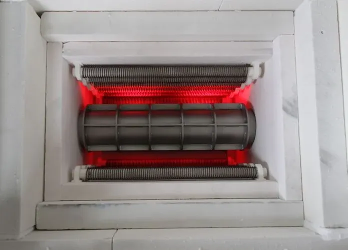 Das Bild zeigt den Heizraum eines Rohrofens der Firma IBT Thermprocess aus Freiberg für industrielle Anwendungen, welcher mit einem metallischen Rohr ausgestattet ist und Prozesse unter Vakuum sowie Prozessgasatmosphäre bis 1200 °C ermöglicht.