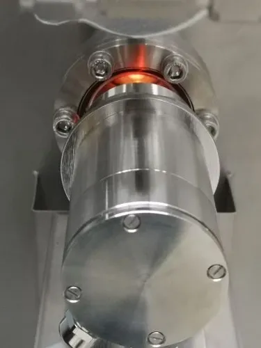 Das Bild zeigt ein Pyrometer der Firma IBT Thermprocess aus Freiberg zur berührungslosen Temperaturmessung bis 3000 °C im Ofenraum, das vor einem vakuumdichten Flansch mit Schauglas installiert ist.